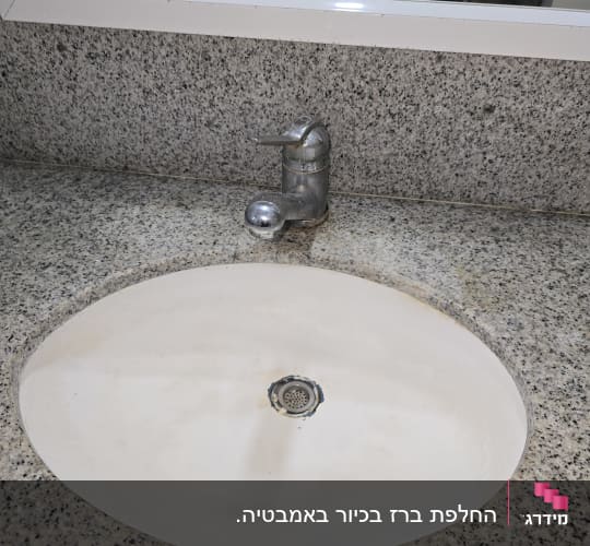 כיור עם ברז מתכת על משטח גרניט